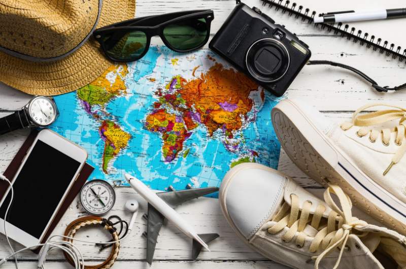 Essential travel items laying out across a world map.