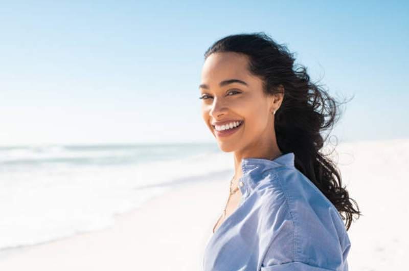 Carefree woman smiling while walking on the beach.