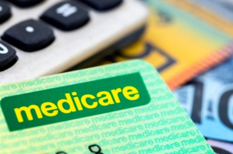 An Australian Medicare card lying on top of a calculator and Australian bank notes