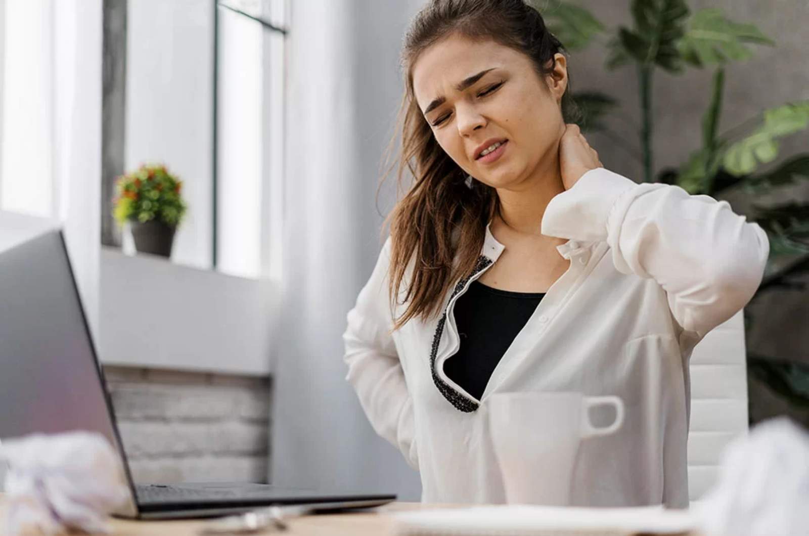 An individual sits uncomfortable in chair as they suffer from chronic pain.