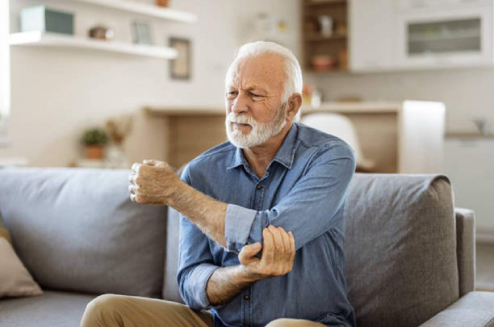 An individual with osteoarthritis holds elbow painfully.