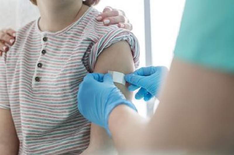 A child receives tetanus vaccination with nurse placing plaster over the vaccination site on arm.