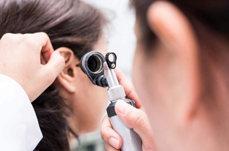 Audiologist checking earwax for patient