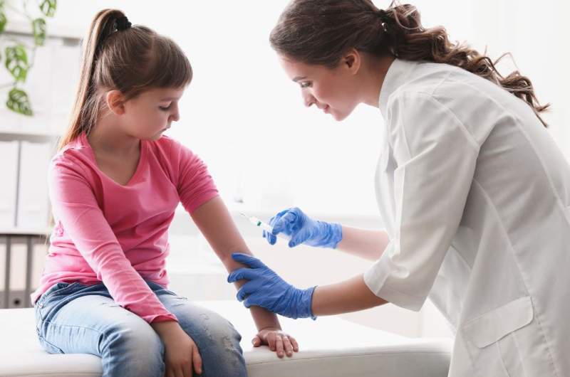 Child receives meningococcal vaccine from nurse