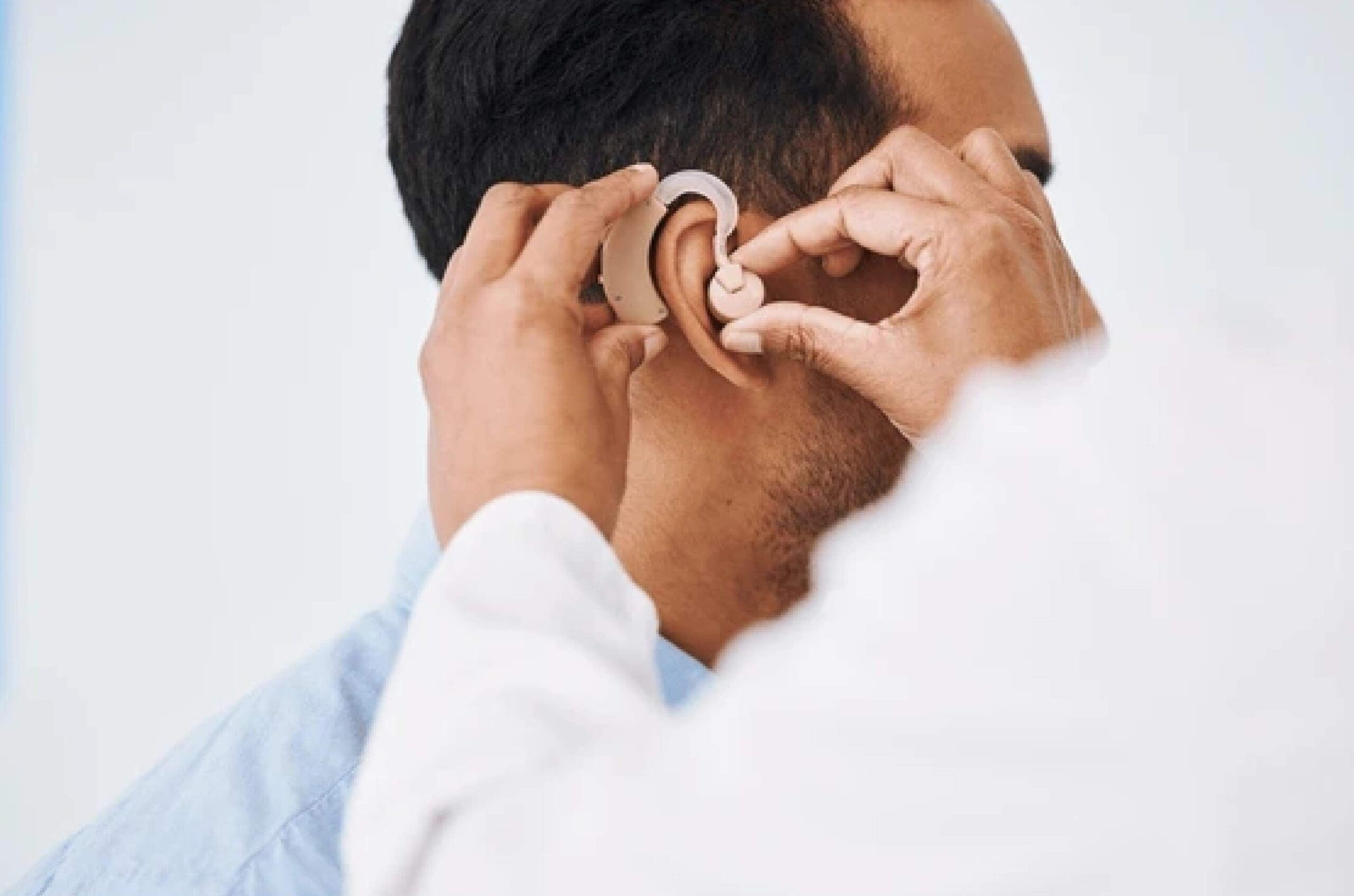 Audiologist-fitting-hearing-aid-on-patient Audiologist fitting hearing aid on patient.