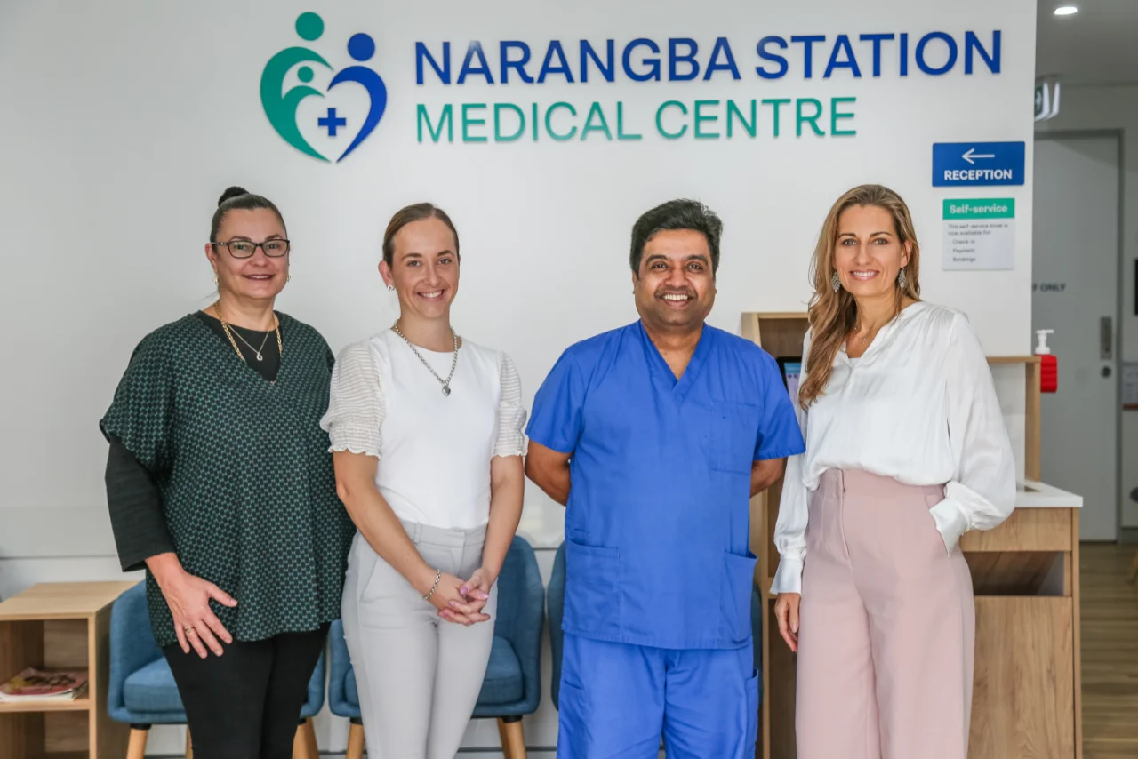 Dr Madhu Lakshmaiah and his team standing and smiling in front of Narangba Station Medical Centre sign - open 7 days and after hours appointments available.